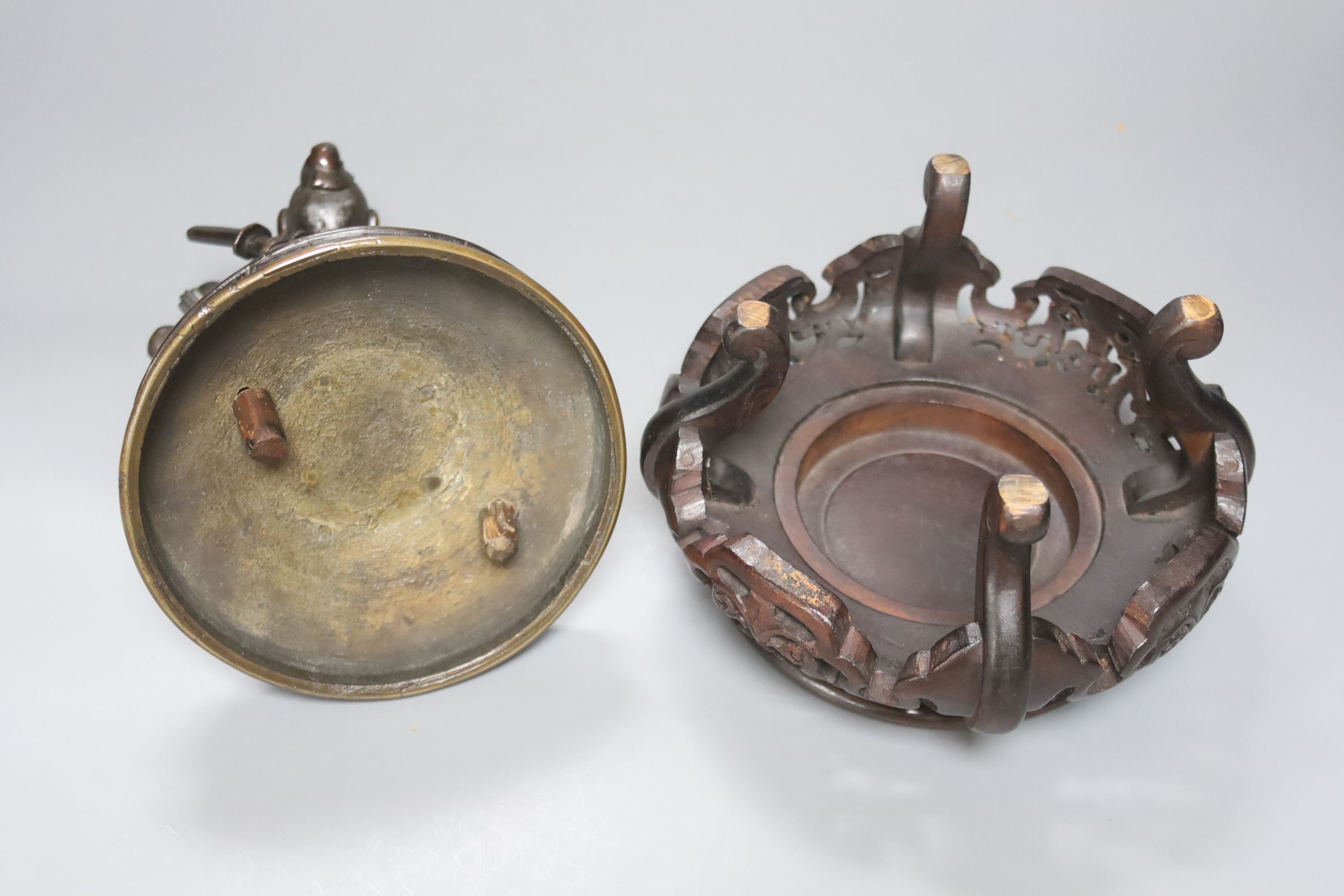 A Japanese bronze cover modelled as a samurai general, Meiji period, holding a fan and a ball, wood stand 28cm total height